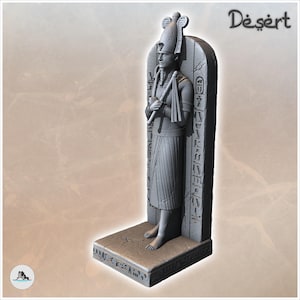 May include: A grey statue of an Egyptian figure wearing a tall headdress and holding a flail, standing against a vertical stone slab engraved with hieroglyphics. The figure is positioned on a rectangular base with the word Desert in the corner.