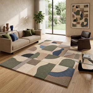 Könnte beinhalten: Ein moderner Wohnzimmerteppich mit einem geometrischen Muster in Beige-, Grün-, Blau- und Brauntönen. Der Teppich ist rechteckig und bedeckt einen großen Teil des Bodens. Das Zimmer verfügt auch über ein Sofa, einen Sessel und Kunstwerke.