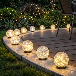 May include: A series of spherical solar garden lights with a crackled glass texture, each emitting a warm yellow glow. These round, illuminated globes are arranged along the curved edge of a stone patio, providing soft lighting for the outdoor space.