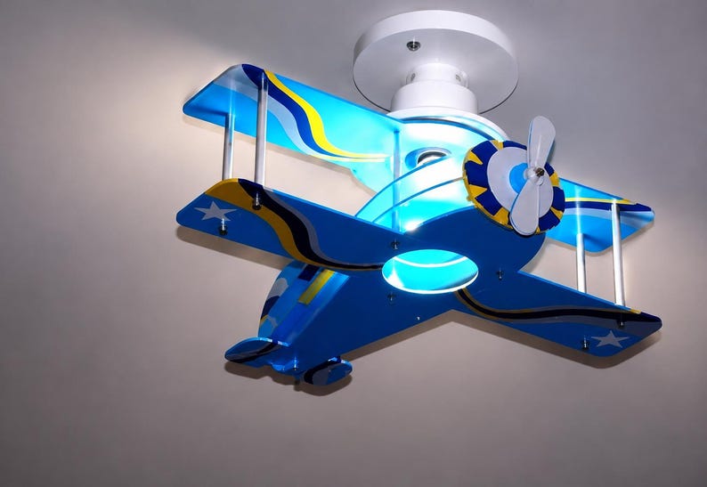 Peut inclure: Un plafonnier en forme de biplan bleu avec des accents jaunes et blancs. L'avion pr&eacute;sente une h&eacute;lice blanche, deux jeux d'ailes et des graphismes d'&eacute;toiles blanches sur le bout des ailes. Il est fix&eacute; au plafond par une base blanche.