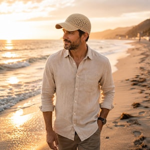 Puede incluir: Una gorra de béisbol de ganchillo en color beige con un patrón de tejido abierto y texturizado y una visera curva. La gorra presenta una corona estructurada y una puntada consistente, ofreciendo un accesorio de tono neutro con una silueta deportiva.