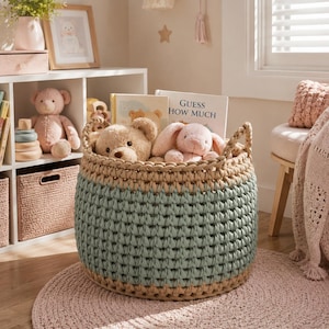 May include: A round, two-toned crochet basket in shades of blue and beige, filled with stuffed animals and books. The basket sits on a pink rug, with a bookshelf and other decorative items in the background. The book reads "Guess How Much".
