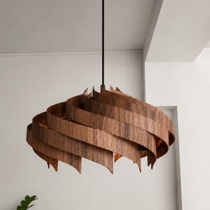 Puede incluir: Una lámpara colgante que presenta una serie de listones de madera curvados en espiral en un tono marrón intenso. Los listones están dispuestos en una formación circular superpuesta alrededor de una fuente de luz central, suspendida por una varilla negra.