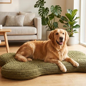May include: A golden retriever dog resting on a large, olive green, bone-shaped pet bed. The bed features a thick, textured, crocheted surface with a distinct rounded edge design, providing a cushioned area for the dog to lie down on the floor.
