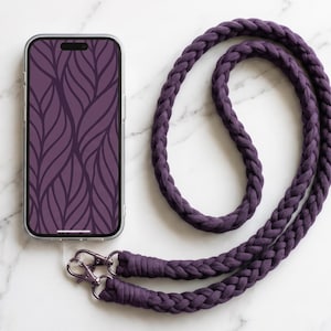 May include: A smartphone with a dark purple leaf-patterned screen display attached to a thick, braided dark purple fabric lanyard. The lanyard features two silver-toned metal swivel clasps that connect the braided cord to the phone case.