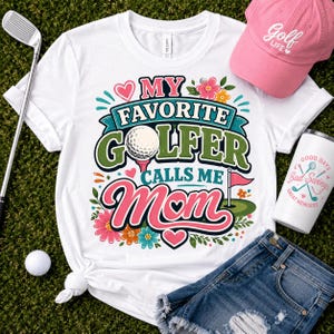 A white t-shirt with a graphic print that reads My Favorite Golfer Calls Me Mom, featuring a golf ball, a flag, and floral accents. The set includes a pink baseball cap with Golf Life text, a golf club, a golf ball, and denim shorts.
