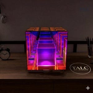 May include: A square infinity mirror lamp featuring a vibrant internal light display with repeating geometric cube patterns in shades of purple, pink, and orange. The device emits a glowing, multi-layered tunnel effect from within its glass frame.