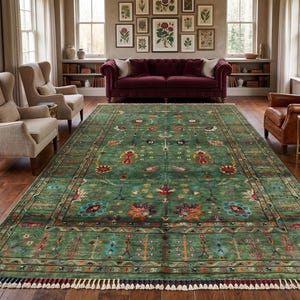Puede incluir: Una alfombra rectangular grande con un fondo verde intenso y un patrón floral y de enredaderas multicolor. La alfombra tiene un borde decorativo y un acabado de flecos con borlas alternas oscuras y claras en los extremos cortos.