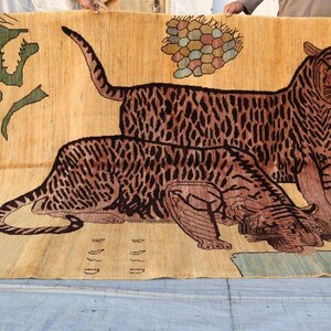 May include: A large rectangular area rug with a tan background featuring two prominent tigers in black and brown stripes. One tiger stands while the other lies down. The rug includes green foliage, a colorful geometric cluster, and abstract shapes.