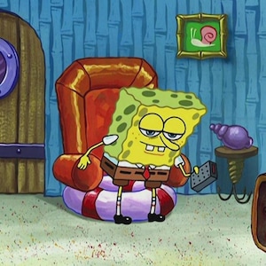 May include: SpongeBob SquarePants cartoon character sitting in a red armchair with a remote control. He is wearing a brown suit, a red tie, and black shoes. The chair is on a red and white striped cushion. A purple seashell sits on a small table.