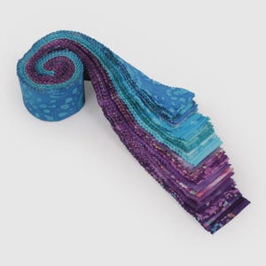 May include: A jelly roll of fabric strips featuring a gradient of colours ranging from deep purple and magenta to bright turquoise and light blue. The fabric pieces display various abstract patterns, including mottled textures and organic shapes.