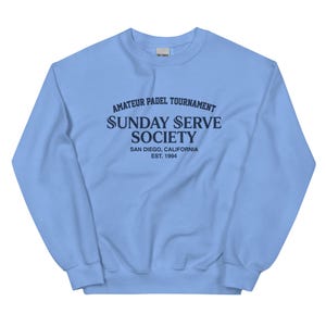 Könnte beinhalten: Hellblaues Sweatshirt mit marineblauem Text: "AMATEUR PADEL TOURNAMENT SUNDAY SERVE SOCIETY SAN DIEGO, CALIFORNIA EST. 1994". Das Sweatshirt hat einen Rundhalsausschnitt und lange Ärmel.
