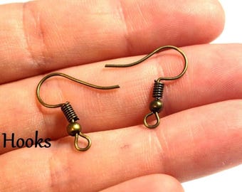 May include: Two antique bronze-colored earring hooks. Each hook has a curved wire, a coiled spring, and a small bead. The hooks are designed for jewelry making and are shown against a skin-toned background.