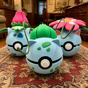 May include: Three spherical light blue containers shaped like creatures with plant-like features on top. Each has a central black and white circular button, green leaf accents, and a thin curved vine. One features a pink bud, one a green bulb, and one a pink flower.