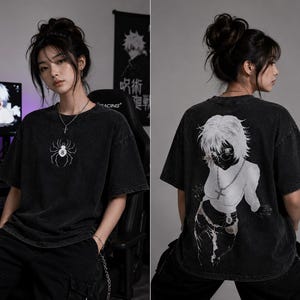 以下が含まれることがあります： 前面に白いクモのグラフィック、背面に白いアニメ風イラストがプリントされた黒い半袖Tシャツ。 ヴィンテージ感のあるウォッシュ加工が施されており、黒いカーゴパンツと合わせています。