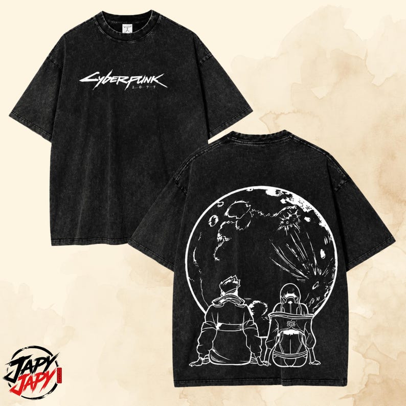May include: A black acid-wash short-sleeve t-shirt featuring the white Cyberpunk 2077 logo on the front chest. The back of the shirt displays a large white graphic of two figures sitting and looking up at a detailed full moon in the night sky.