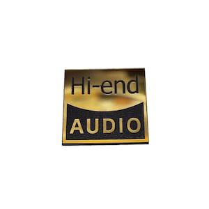 May include: A square metallic gold and black sticker or emblem featuring the text Hi-end in black on the top gold section and the word AUDIO in gold on a black background at the bottom, with a curved line separating the two distinct sections.