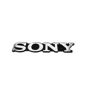 Op de afbeelding: Een zilver en zwart SONY-logo, met het woord 'SONY' in een vetgedrukte, schreefloze lettertype. De letters zijn zilverkleurig met een reflecterende kwaliteit, tegen een zwarte achtergrond. Het logo is gecentreerd op een witte achtergrond.