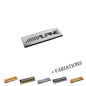 May include: A rectangular metal emblem featuring the Alpine logo in black text with five diagonal lines to the left. Below the main emblem, five additional variations are displayed, some including the text CAR AUDIO SYSTEM in black.