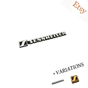 Può includere: Un emblema con il logo del marchio Sennheiser in bianco e nero, caratterizzato dall'icona della lettera S stilizzata seguita dal testo SENNHEISER in lettere maiuscole. L'immagine mostra anche varianti più piccole del logo, inclusa una versione quadrata oro e nera.