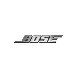 May include: A metallic silver Bose logo emblem featuring a brushed texture and a bold, slanted typeface. The letters are connected with a horizontal line extending from the bottom of the letter B, creating a distinct, recognizable brand mark.