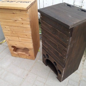 May include: Two wooden dog treat storage containers. The container on the left is light brown wood with the words "Dog Toys" on the lid. The container on the right is dark brown wood.