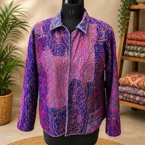 Op de afbeelding: Een jas met lange mouwen en een patchworkontwerp in tinten paars, magenta en roze. Het kledingstuk is voorzien van zichtbaar stiksel in kantha-stijl, een standaard kraag en een knoopsluiting aan de voorzijde.