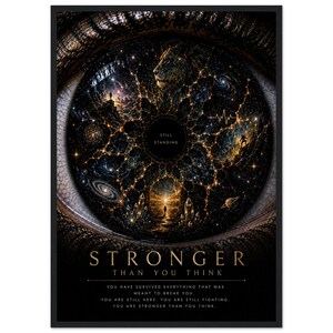 Könnte beinhalten: Ein gerahmter Kunstdruck, der eine menschliche Iris zeigt, gefüllt mit kosmischen Bildern wie einem Löwen, Galaxien und menschlichen Silhouetten. Der Text lautet: STILL STANDING, STRONGER THAN YOU THINK, sowie ein Absatz über das Überleben.