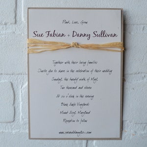 May include: A wedding invitation with a rustic theme. The invitation is printed on cream paper with brown text. The text reads "Plant, Love, Grow" and "Sue Fabian + Danny Sullivan". The invitation also includes the date and time of the wedding, the location, and the website for the couple.