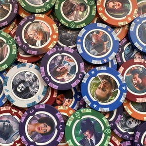 May include: A collection of circular poker chips featuring various character portraits in the center. The chips have colorful, patterned borders in shades of green, blue, orange, and purple, with distinct symbols printed along the outer edges.