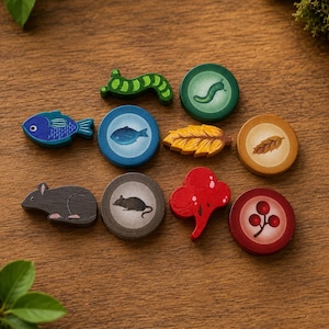 May include: A collection of wooden game tokens featuring various nature-themed shapes and illustrations. The set includes a green caterpillar, a blue fish, a brown mouse, a yellow leaf, a red berry cluster, and matching circular discs with icons.