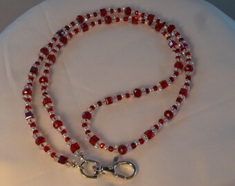 May include: A red and clear crystal beaded lanyard with a silver swivel clasp.