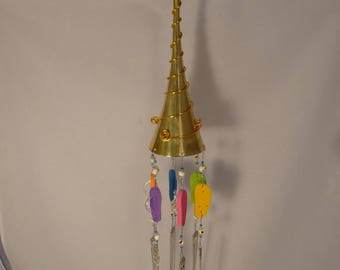 May include: A gold wind chime with a trumpet-shaped top and multiple spoons hanging from it. The spoons are decorated with colorful flip-flops and beads.