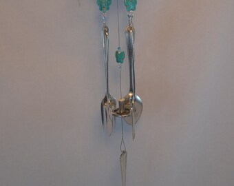 May include: A silver wind chime with a metal top and turquoise butterfly accents. The chime is made from spoons and forks.