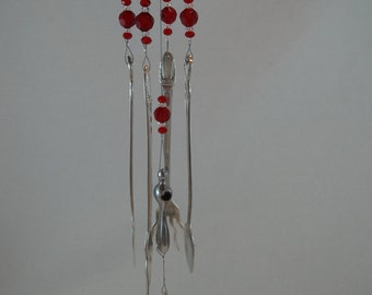 May include: A wind chime made from recycled silverware and red beads. The chime is suspended from a gold-colored metal top with red wire accents.