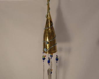 May include: A gold-colored wind chime made from a wine glass with a blue wire wrapped around it. The chime has five silver spoons and a fork hanging from it, with blue and red glass beads.