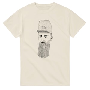 May include: A cream-coloured short-sleeve t-shirt featuring a black and white line art illustration of a face with a long, textured beard and a baseball cap with the word JOHN printed on the front. The graphic is centred on the chest area.