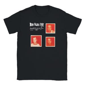 Op de afbeelding: Een zwart t-shirt met korte mouwen en de witte tekst Ben Folds Five en Whatever and Ever Amen. Het ontwerp bevat drie vierkante, roodgetinte fotografische portretten van personen, gerangschikt in een raster op de borst.