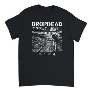 May include: A black short-sleeve t-shirt featuring a white graphic print. The design includes the text "DROPDEAD" at the top, a high-contrast black and white image of a person walking on a path, and Japanese characters at the bottom.