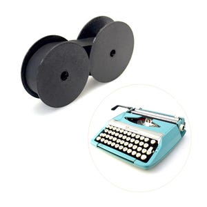 以下が含まれることがあります： 黒いタイプライターリボンとヴィンテージのターコイズブルーのタイプライター。タイプライターは白いキーと黒いキャリッジリターンレバーを備えています。リボンは暗い素材で作られています。