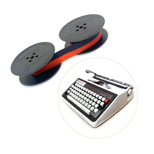 May include: A black typewriter ribbon on two circular plastic spools connected by a red and black ink ribbon, positioned next to a white Brother typewriter with a black keyboard, white keys, and a red carriage return key on the right side.