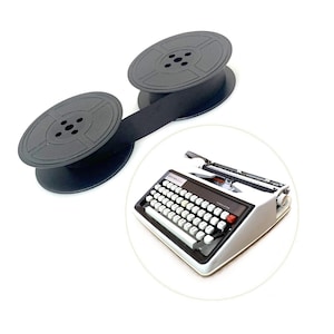 May include: A white Brother typewriter with a black keyboard and a red key, accompanied by two black circular spools connected by a black ribbon. The typewriter features a dark panel above the keys with the brand name Brother clearly visible.