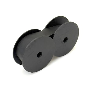 Peut inclure: Une cartouche de ruban pour machine à écrire noire composée de deux bobines circulaires reliées par une bande centrale de tissu noir imprégné d'encre. Les bobines en plastique sont rondes avec un petit trou circulaire au centre de chacune.