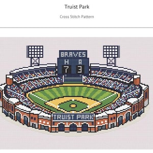 May include: A cross stitch pattern of Truist Park baseball stadium. The design features a green field, blue seating, and a scoreboard displaying 'BRAVES' with the score '7' to '3'. The text 'TRUIST PARK' is visible at the bottom of the stadium.