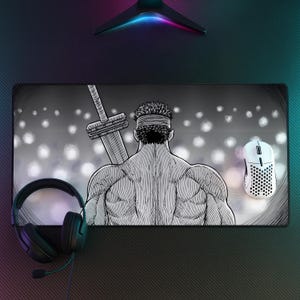 Può includere: Un tappetino da scrivania rettangolare con un'illustrazione in bianco e nero in stile manga di un personaggio muscoloso visto di spalle, che indossa una fascia e porta una grande spada sulla schiena, su uno sfondo di luci bianche sfocate.