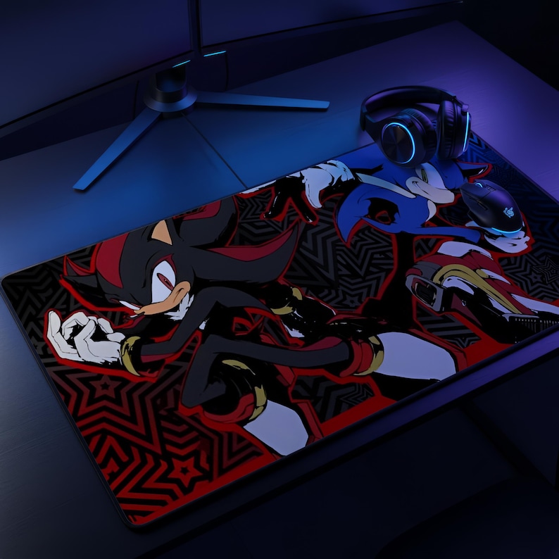 K&ouml;nnte beinhalten: Eine rechteckige Schreibtischunterlage mit einer grafischen Illustration der Charaktere Shadow the Hedgehog und Sonic the Hedgehog vor einem schwarz-roten Musterhintergrund. Eine schwarze Gaming-Maus und schwarze Kopfh&ouml;rer liegen auf der Matte.