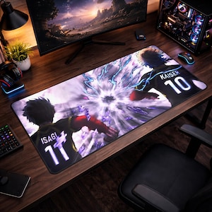 May include: A rectangular gaming mousepad featuring a dynamic anime-style illustration. The design showcases two figures in black and red jerseys, with the names "ISAGI" and "KAISER" and the numbers 11 and 10. The background has a purple and white energy effect.