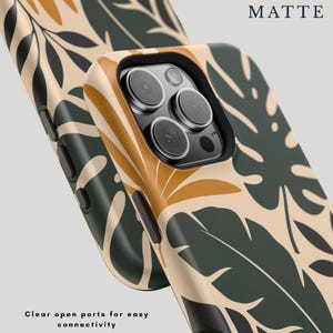 May include: A matte phone case featuring a botanical pattern of dark green and mustard yellow leaves on a beige background. The case has a black camera cutout and black side buttons. Text on the image reads MATTE and Clear open ports for easy connectivity.