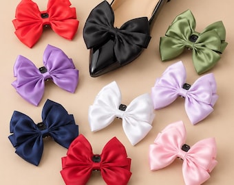 May include: A black pointed-toe flat shoe with a large satin bow attached to the front, surrounded by nine additional loose satin bows in various colors including red, purple, navy blue, olive green, light purple, white, and light pink.