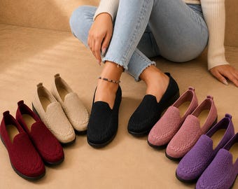 May include: A collection of slip-on loafers featuring a textured knit fabric upper and a solid black sole. The shoes are available in various colors including deep red, beige, black, dusty rose, and purple, all showcasing a rounded toe design.